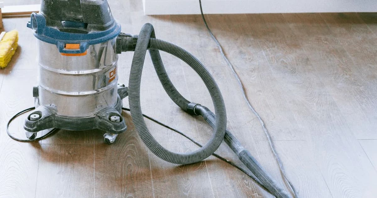 Industrial wet and dry vacuum and a stiff broom on a bare floor during an after builders clean