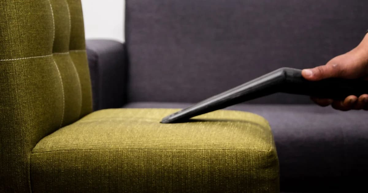 Upholstery cleaning tool lifting soil from a fabric sofa cushion